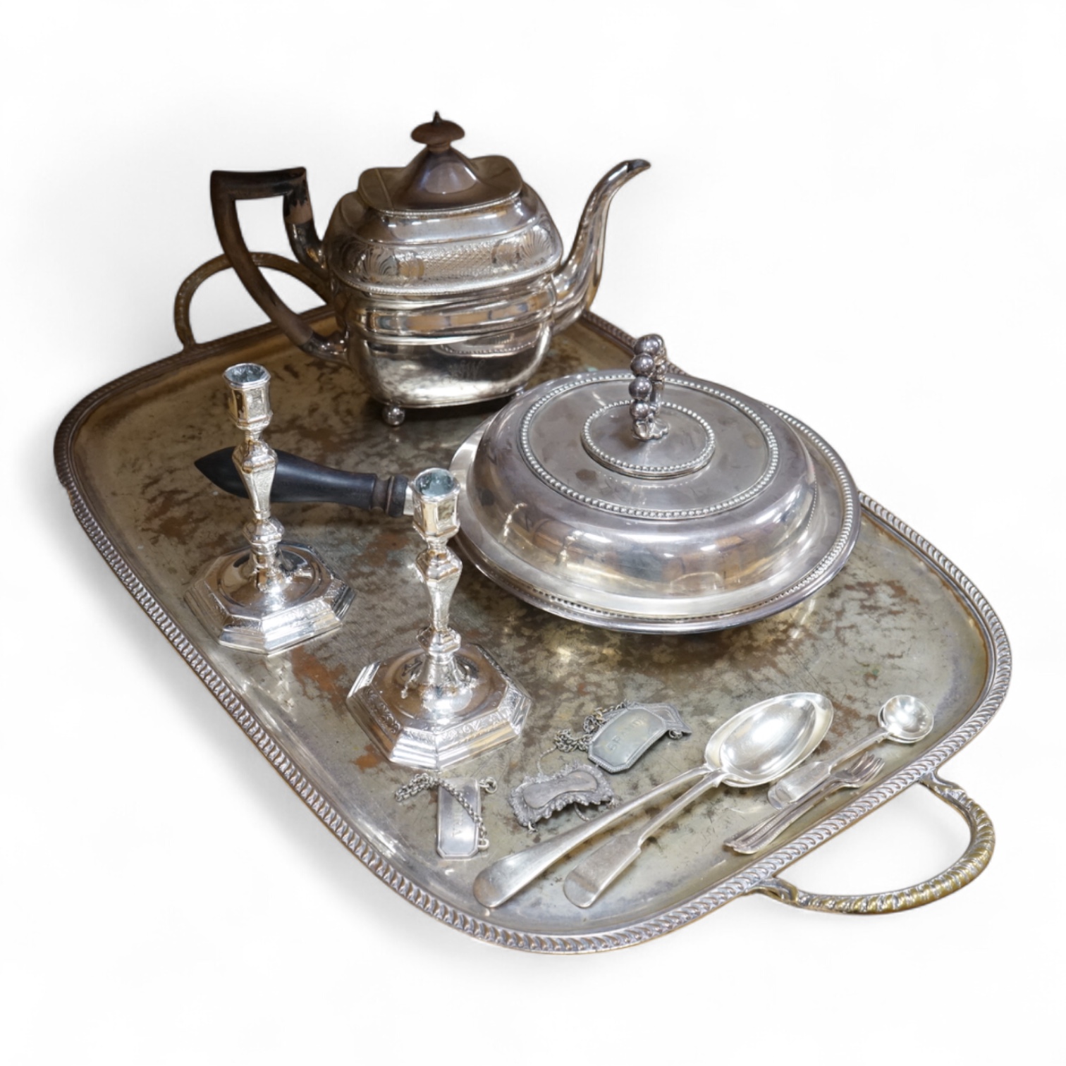 A pair of white metal candlesticks, a silver plated teapot circular tureen and cover spoons and forks and four spirit labels and large tray. Tray 73cm wide